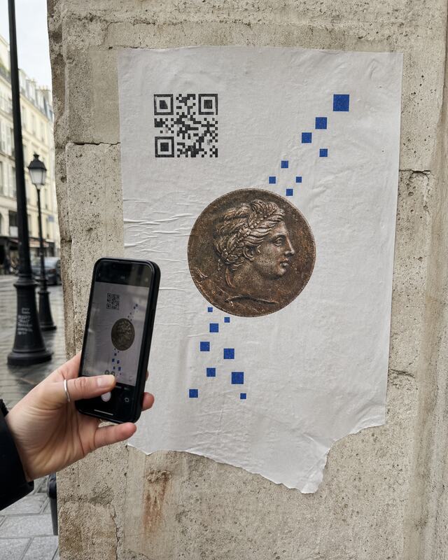 Illustrative participant scanning a temporary MONETA wheatpaste poster in Paris